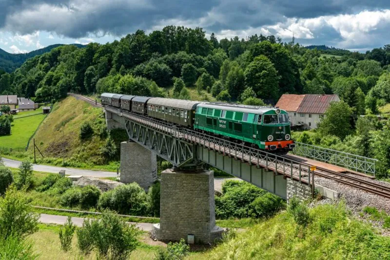 Zabytkowy pociąg jadący po torach na wiadukcie kolejowym