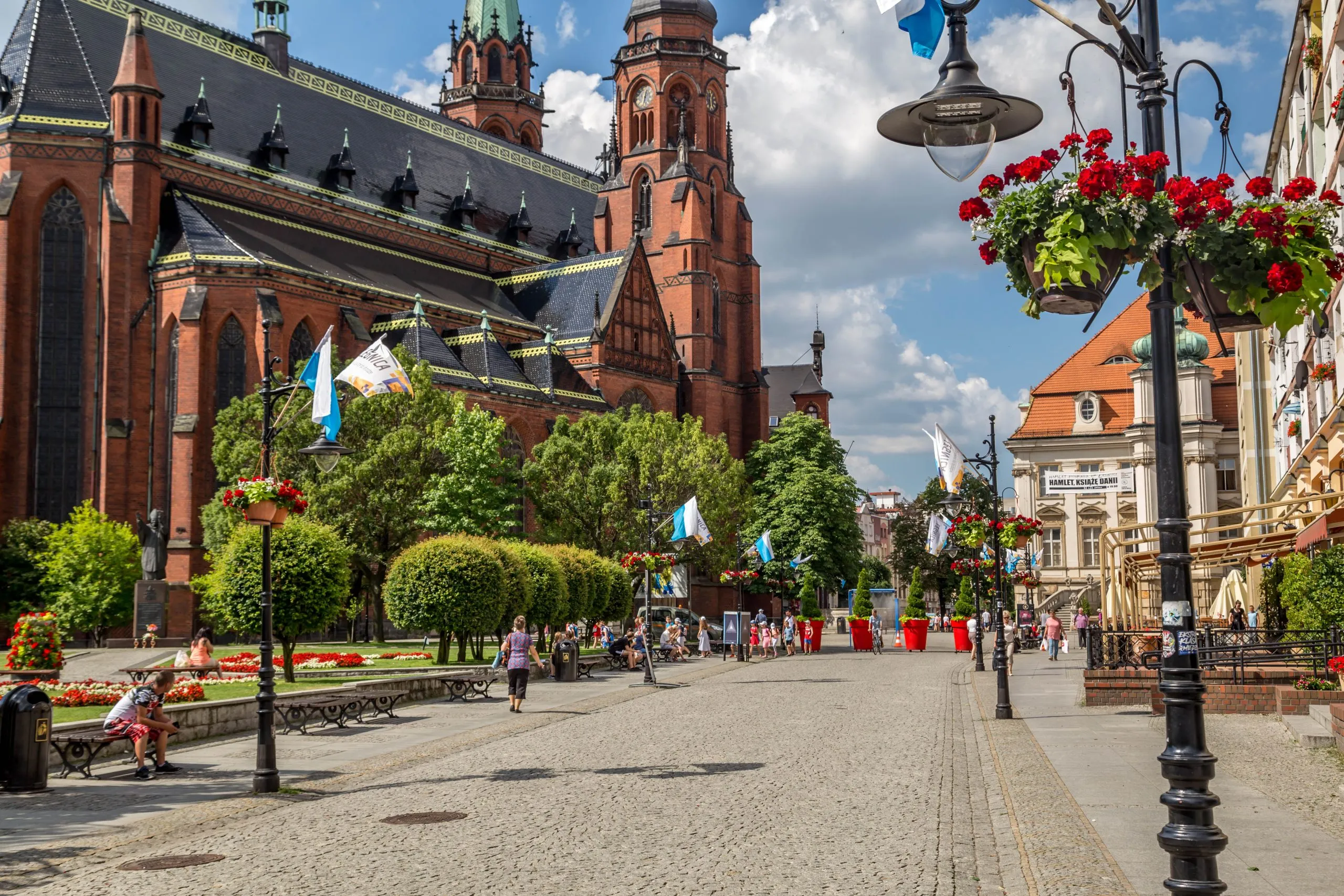 تُظهر الصورة ممشىً واسعًا في ليغنيتسا (Legnica)، مع كنيسة مبنية من الطوب تظهر في الخلفية