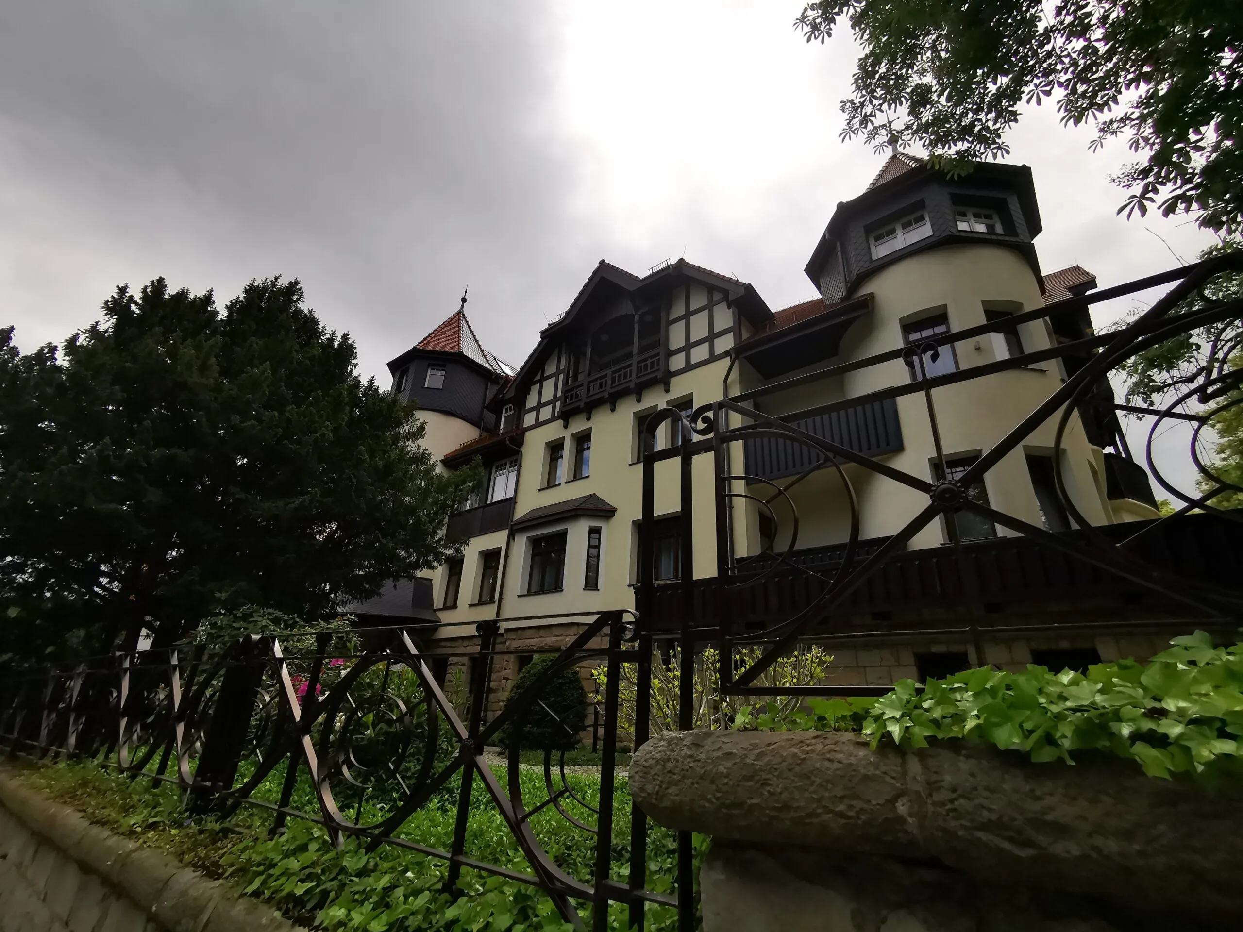 L'Hotel Bukowy Park a Polanica-Zdrój ha una facciata chiara con dettagli in legno scuro, balconi e torrette, circondato dal verde umido del giardino.