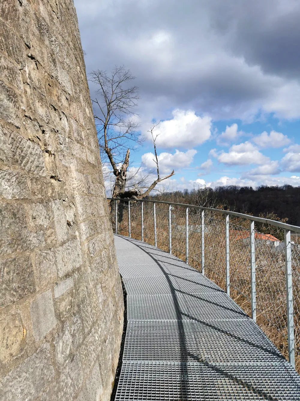 Widok na kładkę trasy okalającej zewnętrzny mur Twierdzy Kłodzko z widokiem na zabudowania Kłodzka