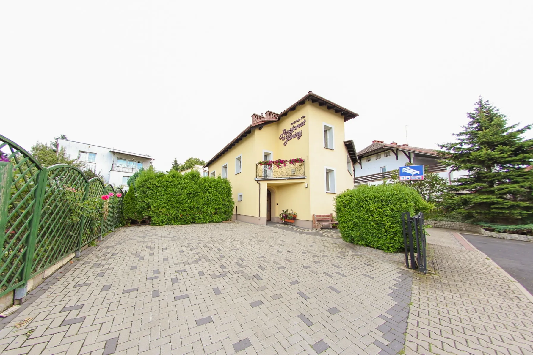 Widok na parking oraz dwukondygnacyjny budynek, z balkonem 