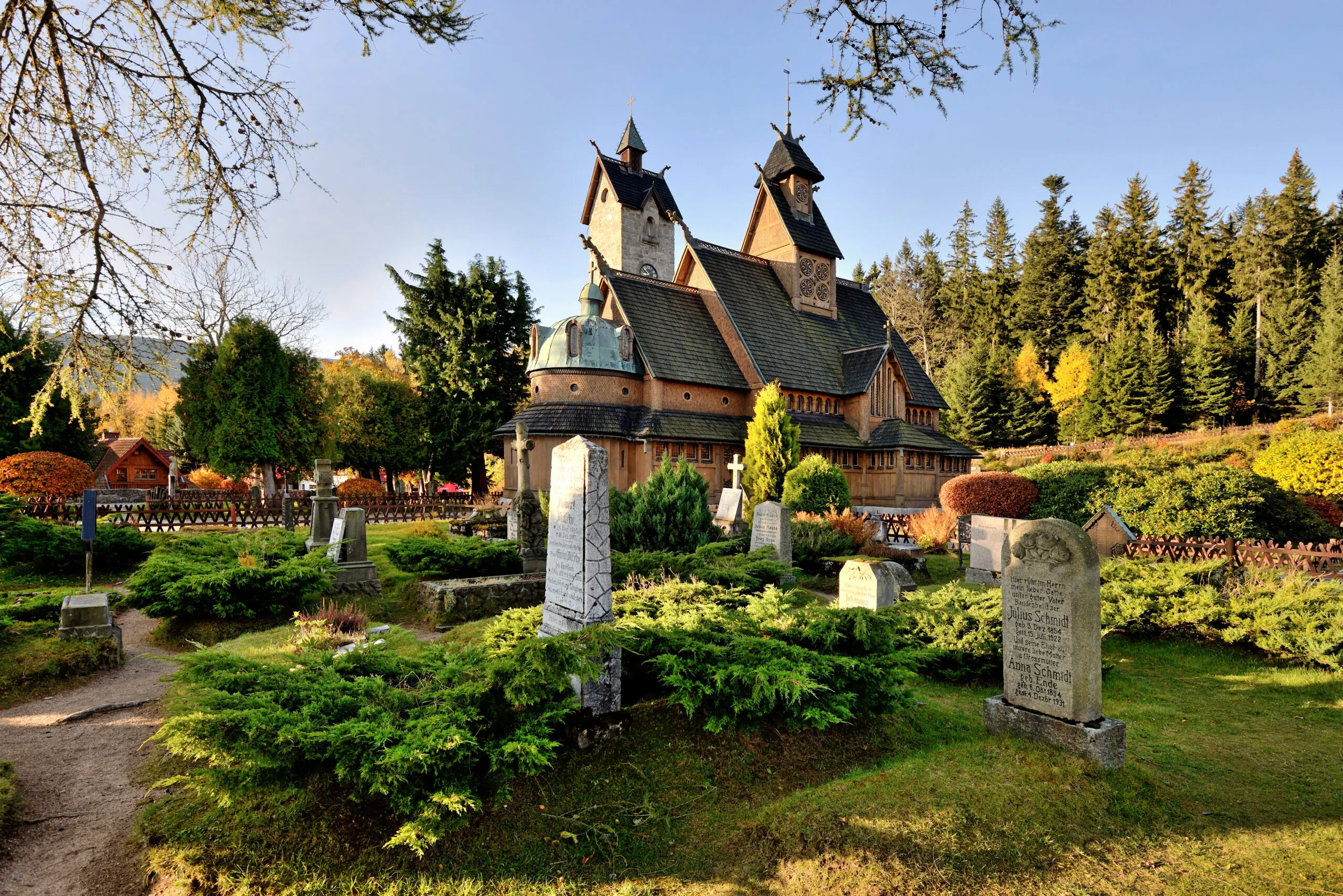 Photo d'une petite église en bois, entourée d'un cimetière historique et d'un cadre naturel
