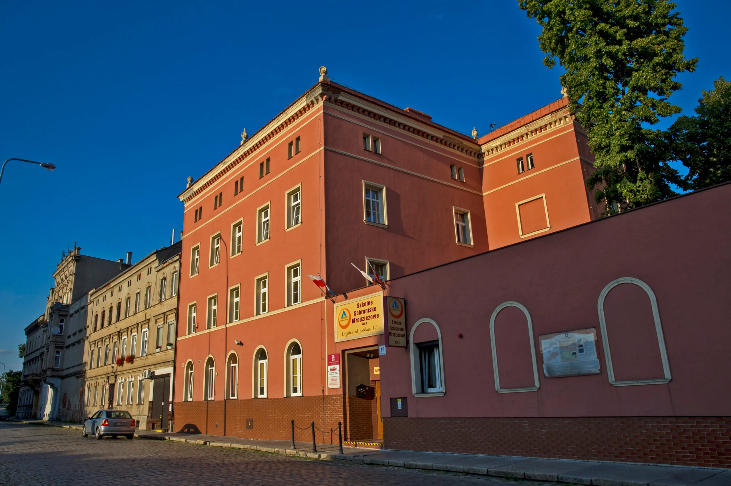 Trójkondygnacyjny, prostokątny budynek połączony z murem