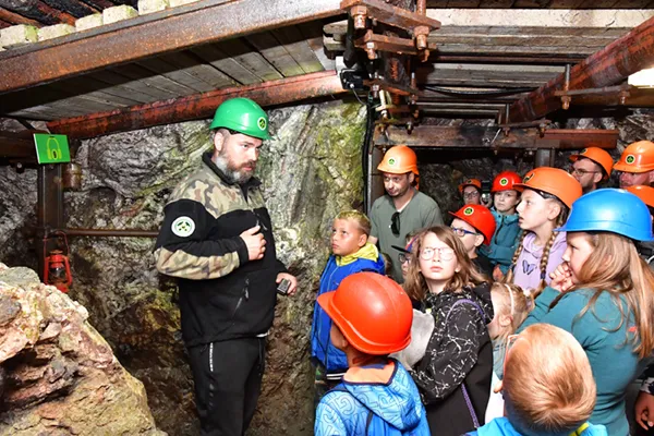 Przewodnik opowiada w podziemiach dawnej kopalni dzieciom historię wydobycia