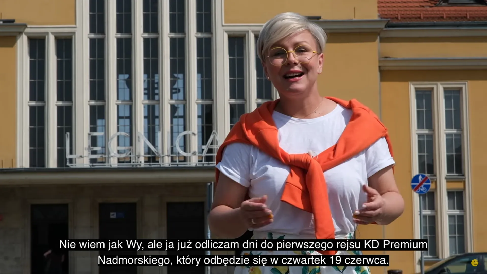 Prowadząca materiał kolejowy mówi przed zabytkowym budynkiem o pierwszym kursie pociągu KD Premium z Wrocławia, zapraszając podróżnych nad morze.