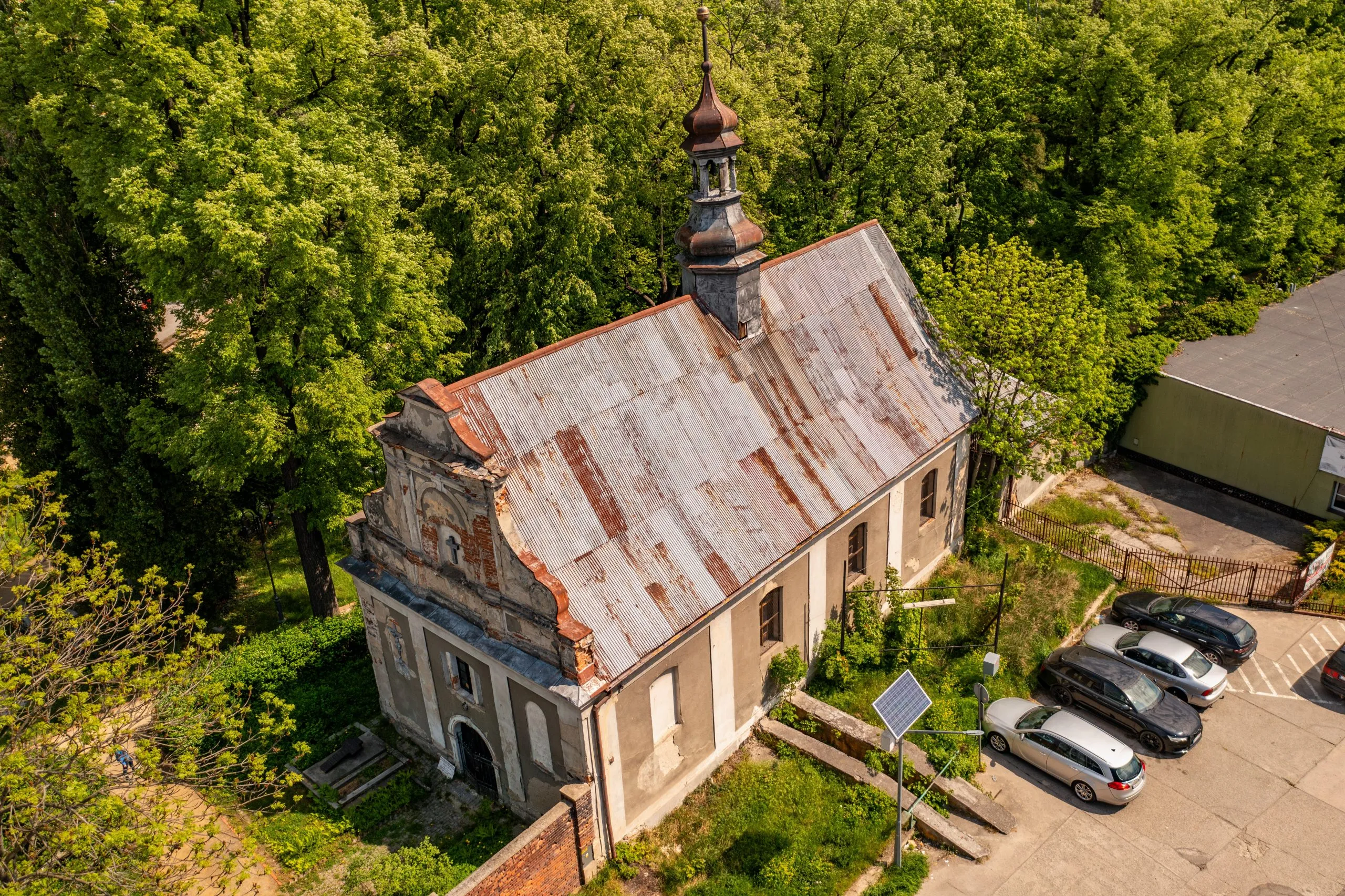 Na zdjęciu z lotu ptaka widać okazały, gotycki kościół z wysoką wieżą i ceglanymi murami, górujący nad zabytkowym centrum Ząbkowic Śląskich.
