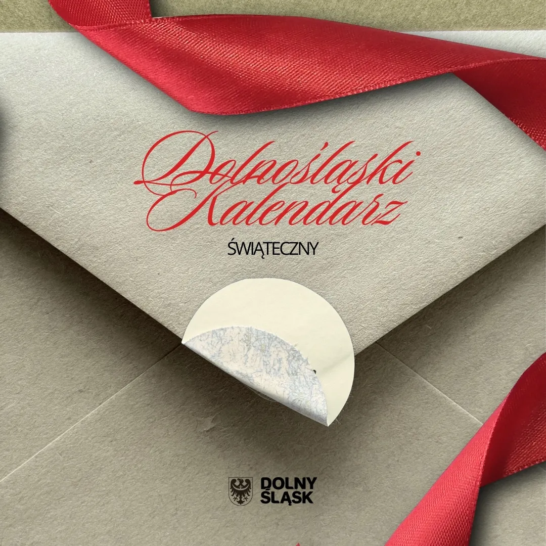 Elegancka zapowiedź konkursu „Dolnośląski Kalendarz Świąteczny” pokazuje beżową kartę z czerwonym odręcznym napisem, ułożoną na czerwonej tkaninie.